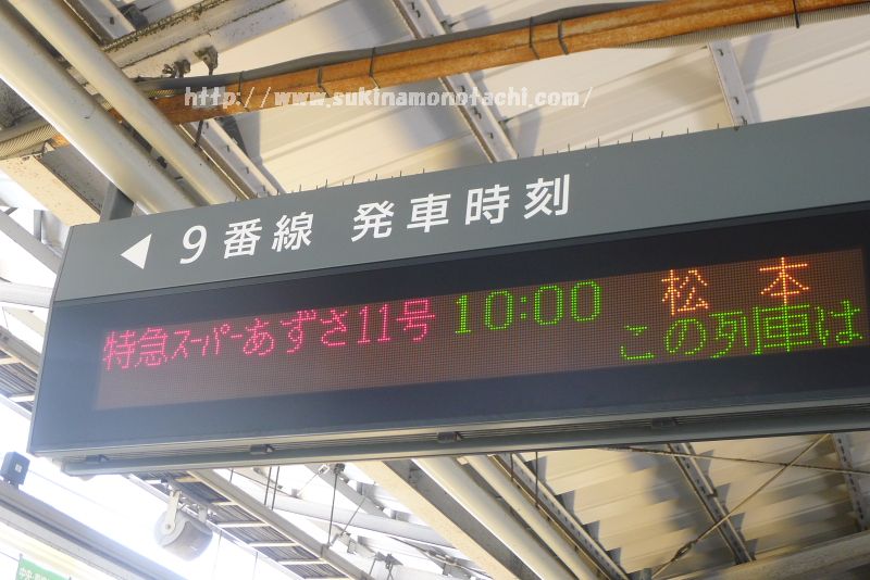 新宿駅の電光掲示板　特急あずさの発車時刻が表示されている